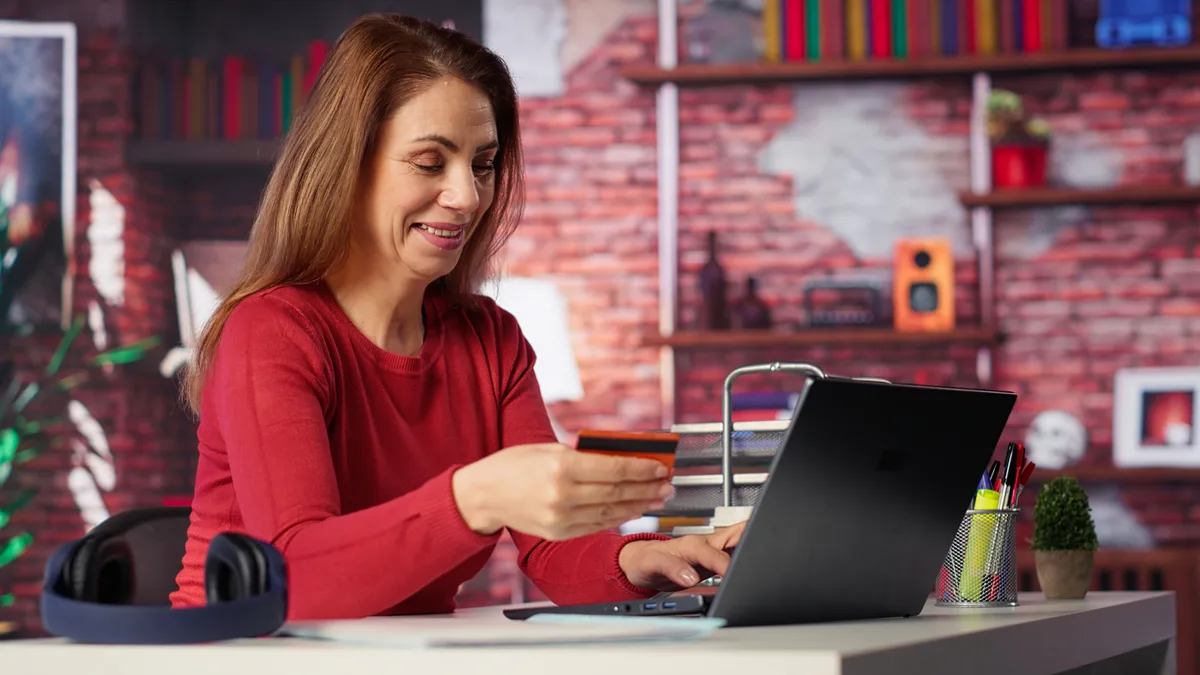 Someone at a desk checking a card while paying for an order online