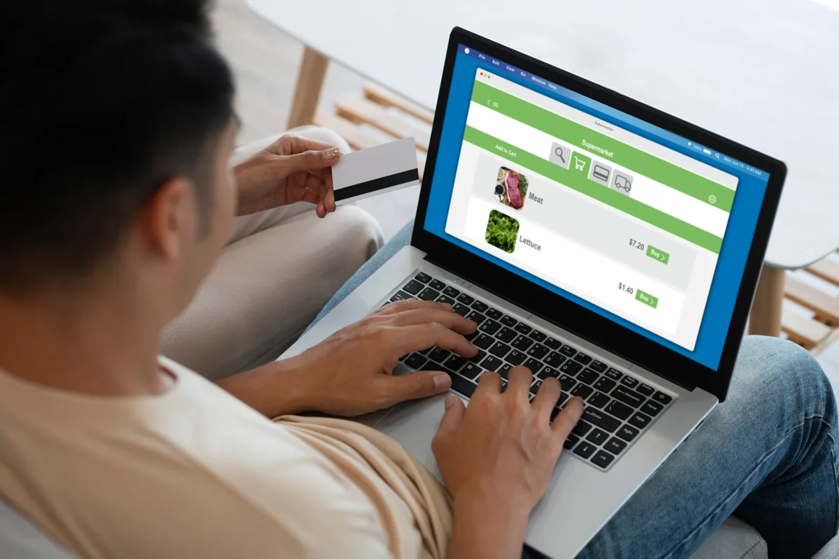 Someone holding a payment card while browsing an online store on a laptop