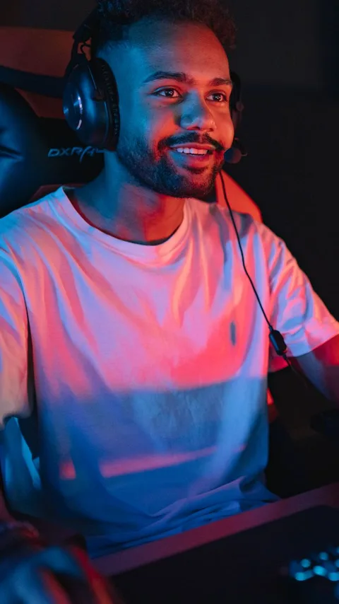 A streamer in a headset mid-session at a lit gaming PC