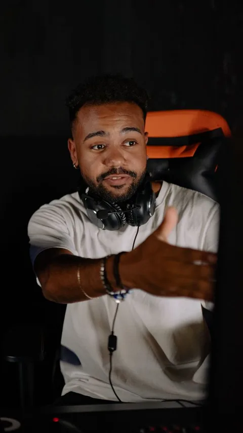 A creator with headphones around their neck talking to camera and gesturing while giving a verdict