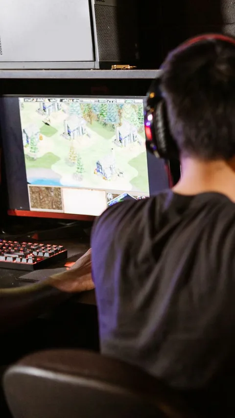 A player in a gaming headset working through a strategy game on a monitor, shot over the shoulder