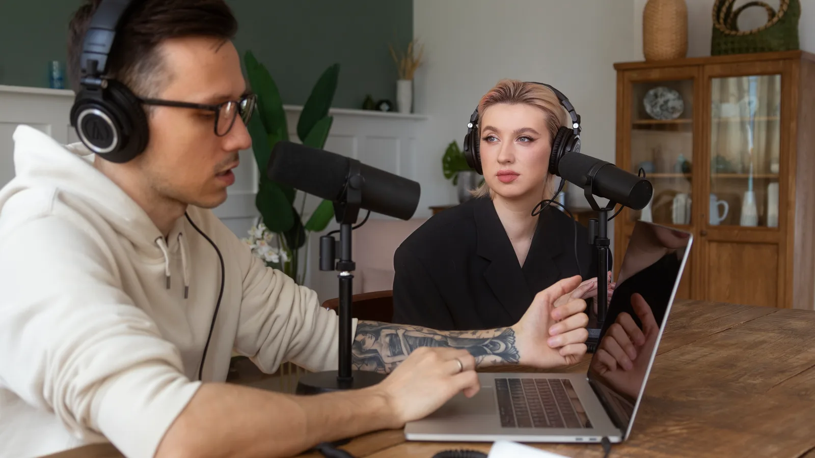 The 16:9 landscape source video: two podcast hosts seated across a table with microphones